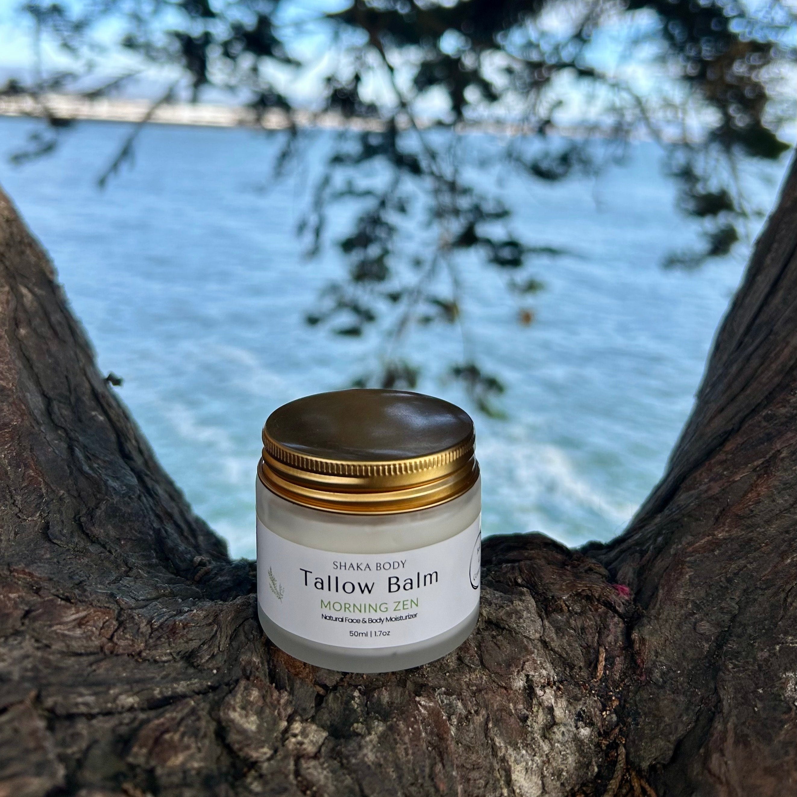 Jar of Tallow Balm on a tree branch with a lake and sky background